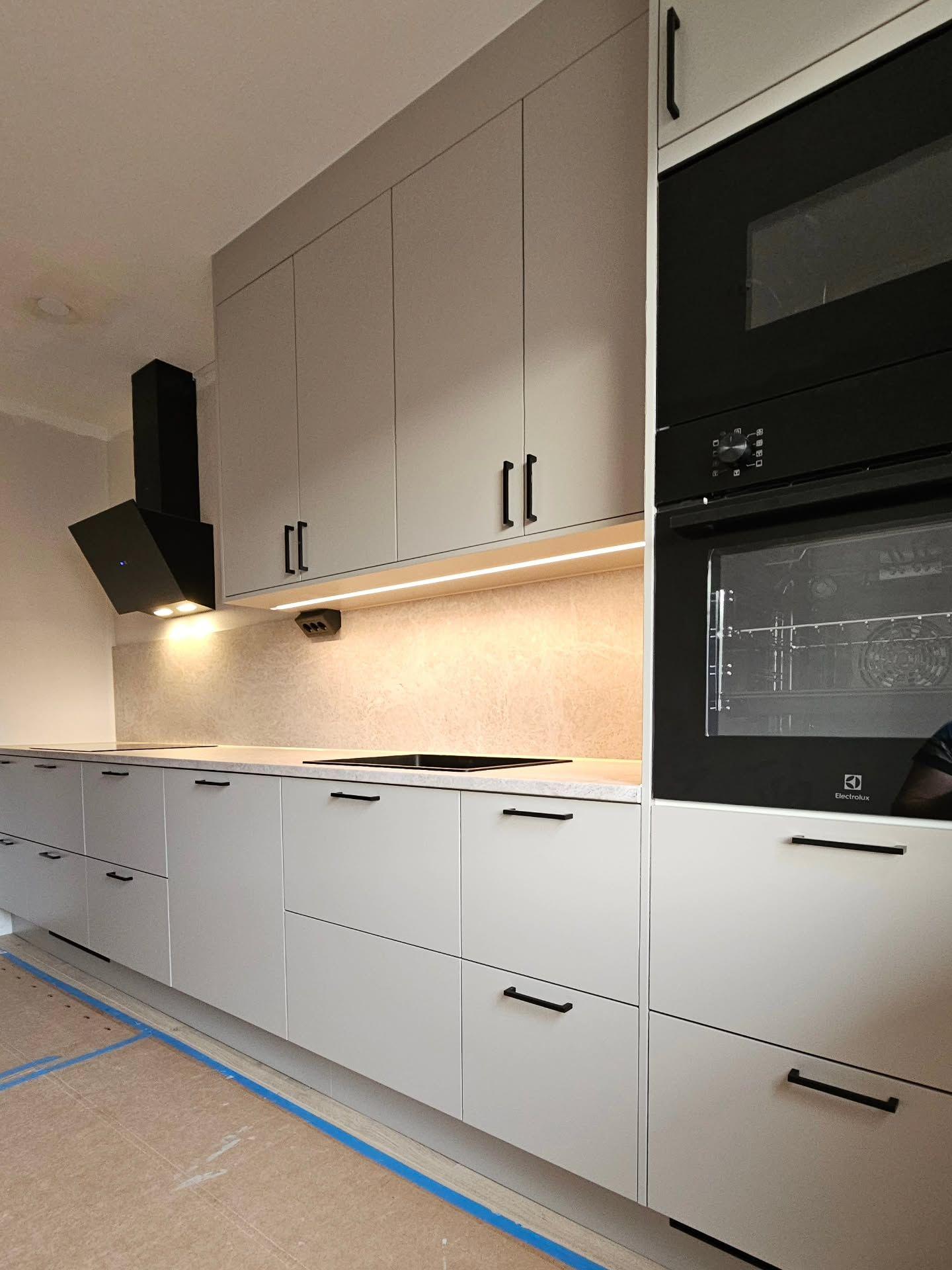 Köksrad med greige luckor, svarta handtag och inbyggd Electrolux-ugn