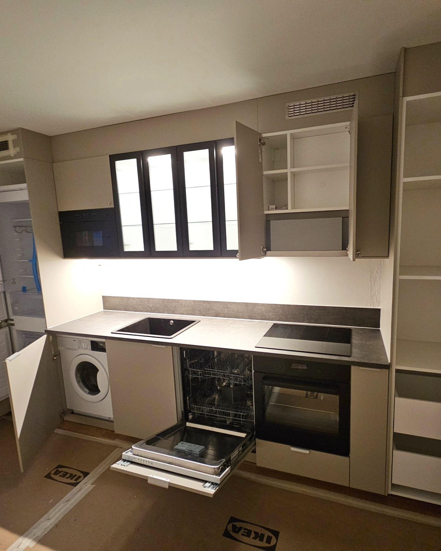 Köket med öppna luckor som visar tvättmaskin, diskmaskin och inbyggd ugn