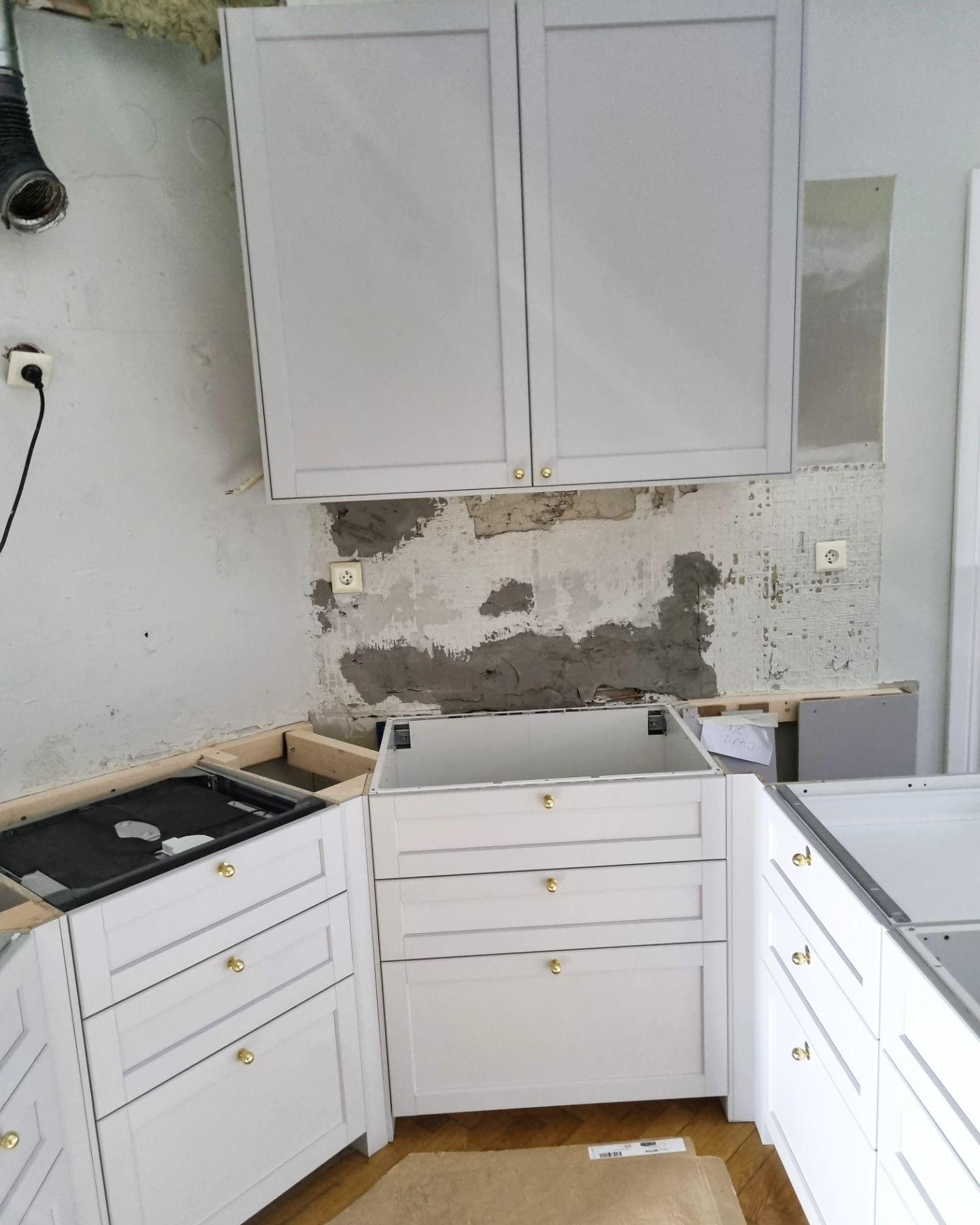Närbild på köksdel med överskåp och putsad vägg bakom bänken