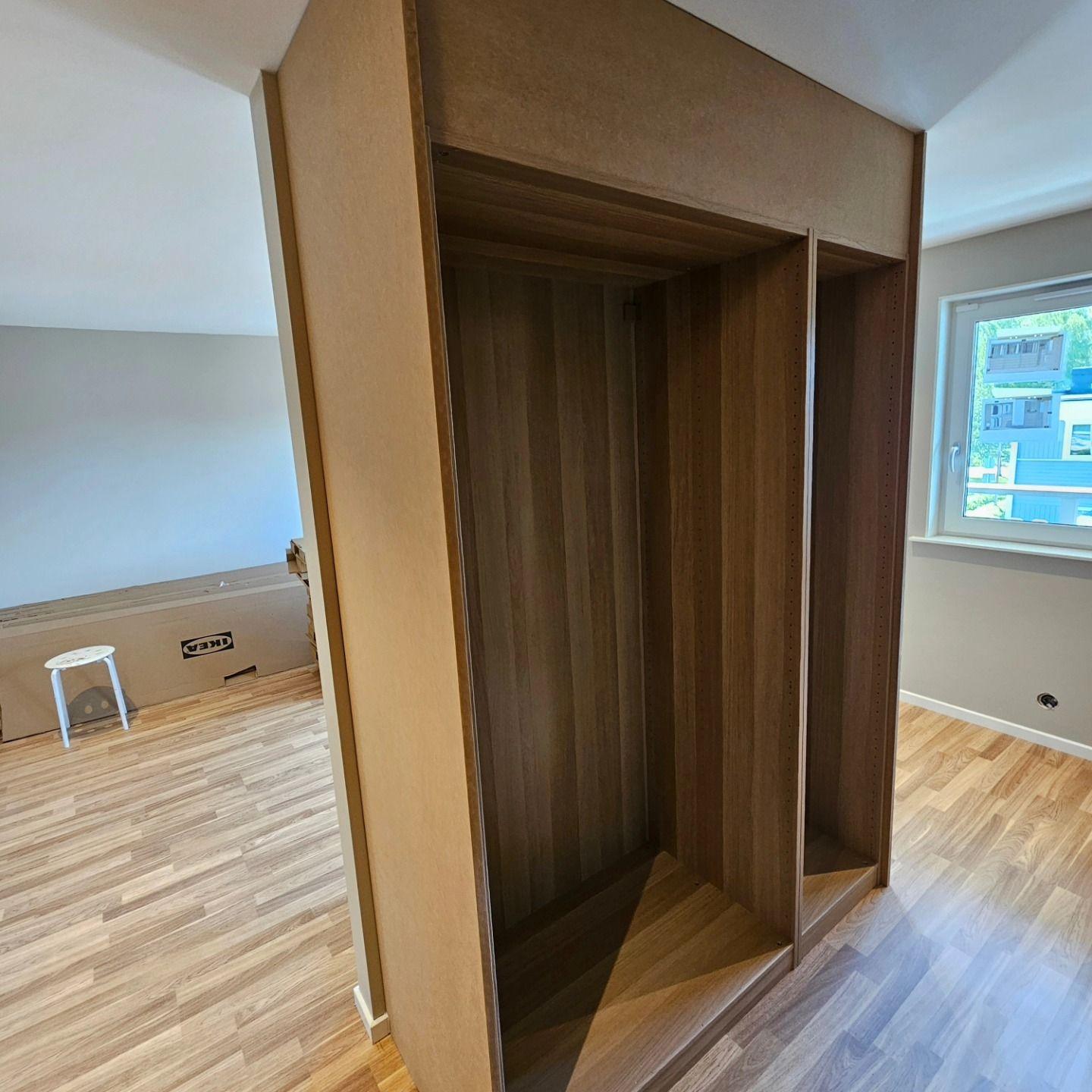 Garderobsstommar på plats i rum med fönster och laminatgolv