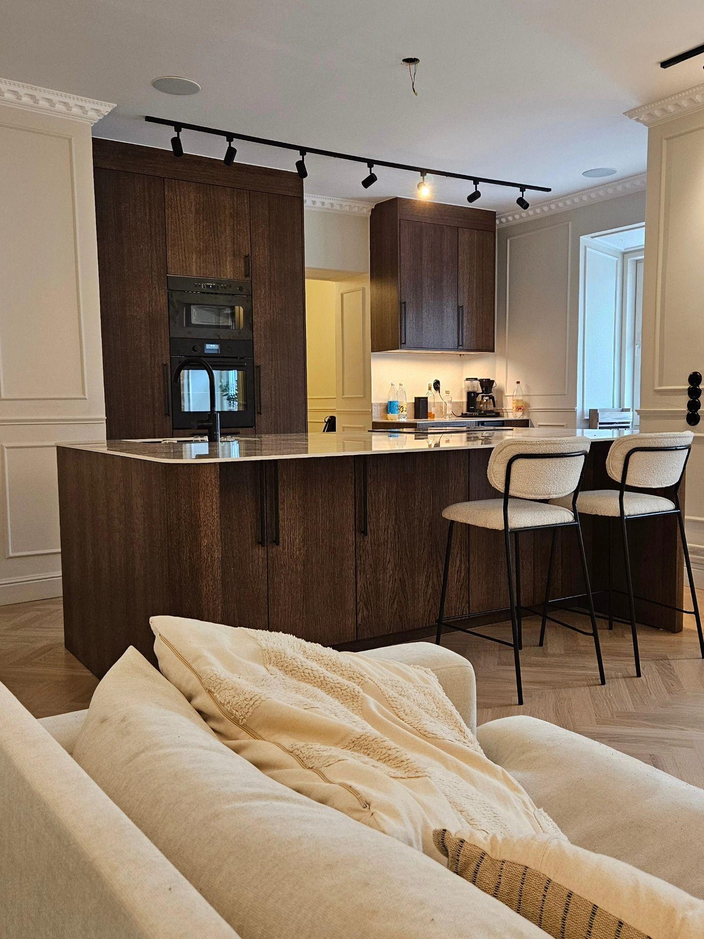 Köksö i mörk ek med ljus stenskiva sett från vardagsrummets soffa