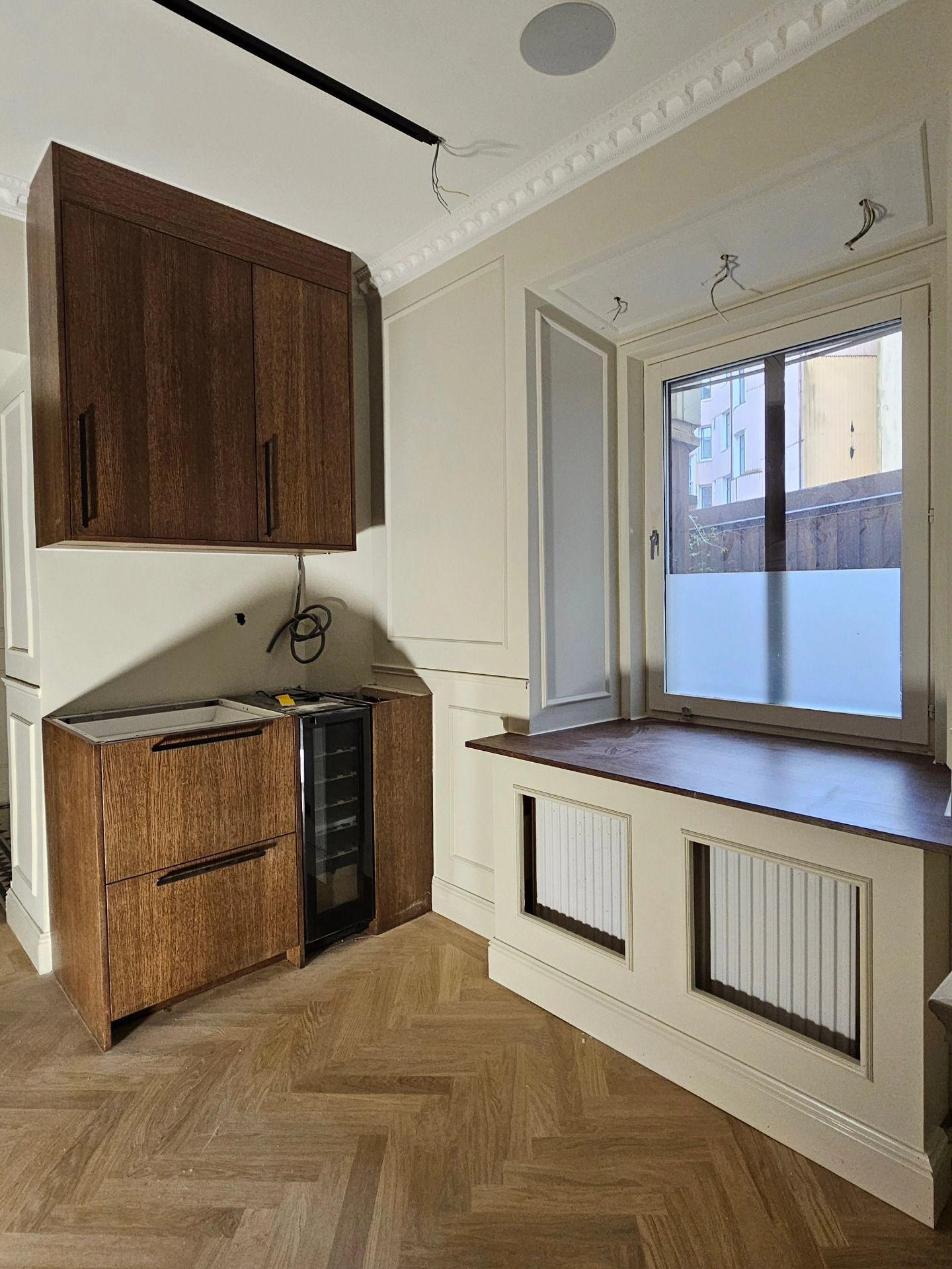 Kaffehörna under installation intill fönster med platsbyggd radiatorkåpa