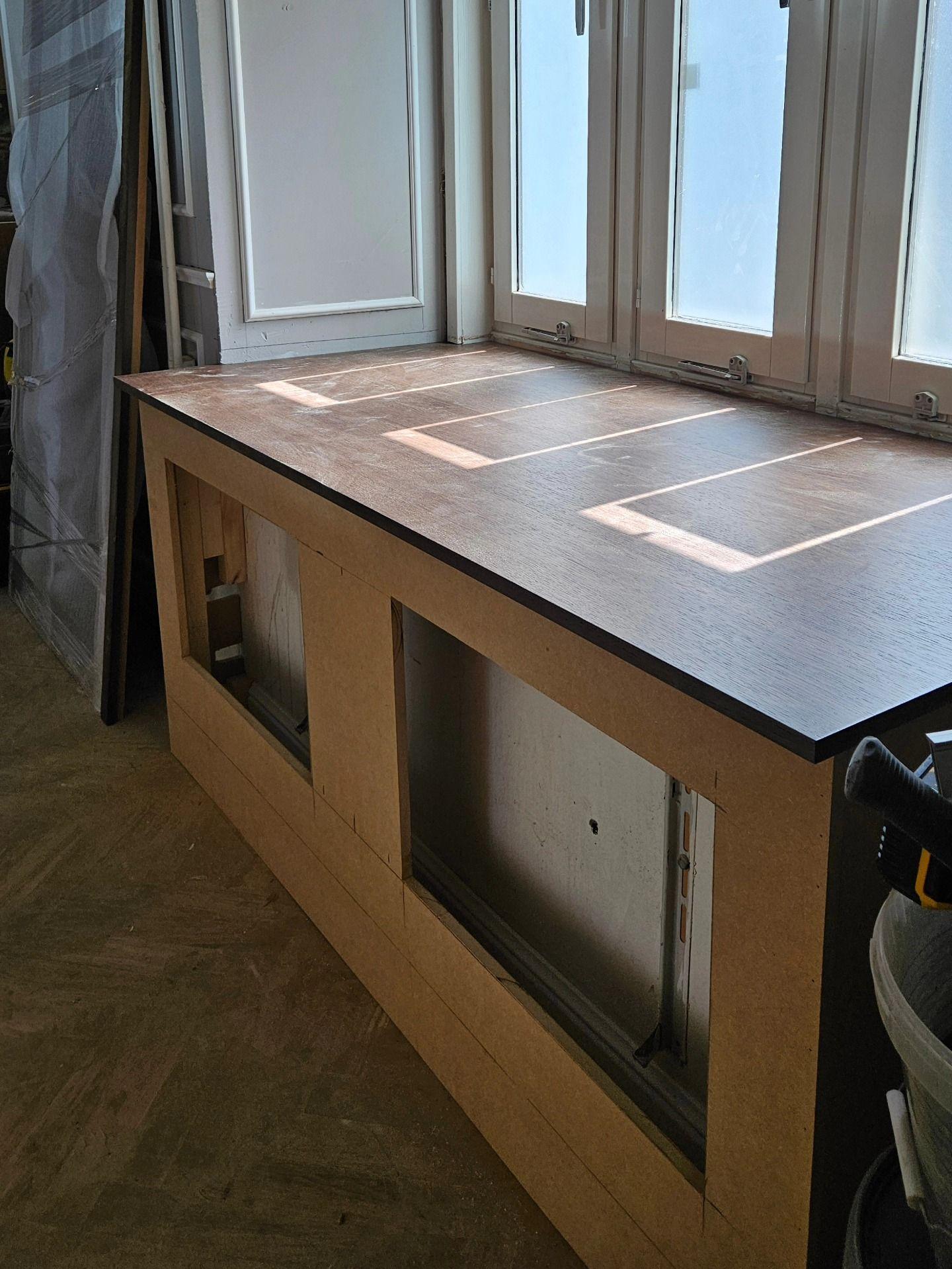 Närbild på mörk bänkskiva ovanpå omålad radiatorinklädnad