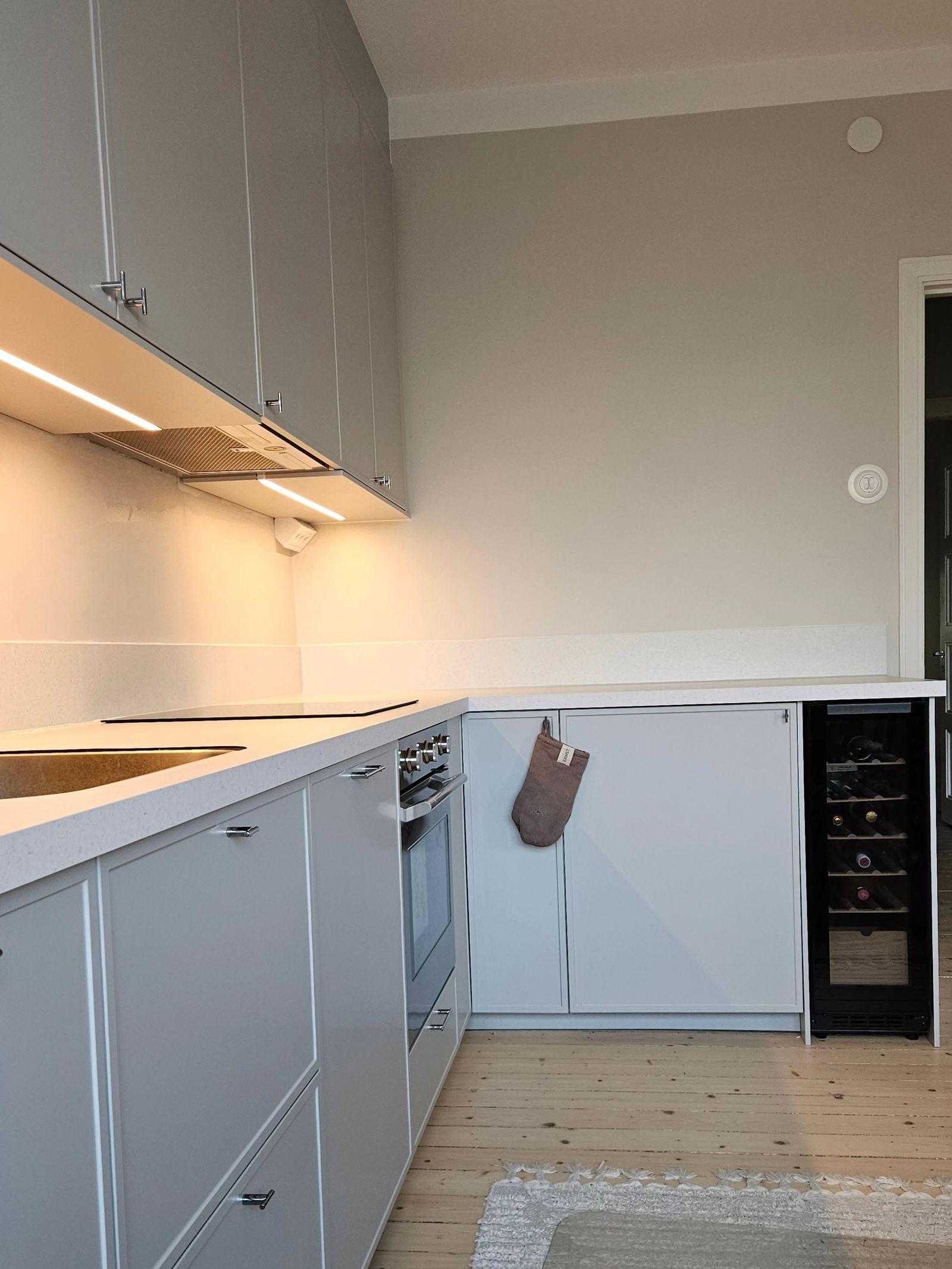 Vinkeldelen av köket med inbyggt vinkylskåp och ljus bänkskiva