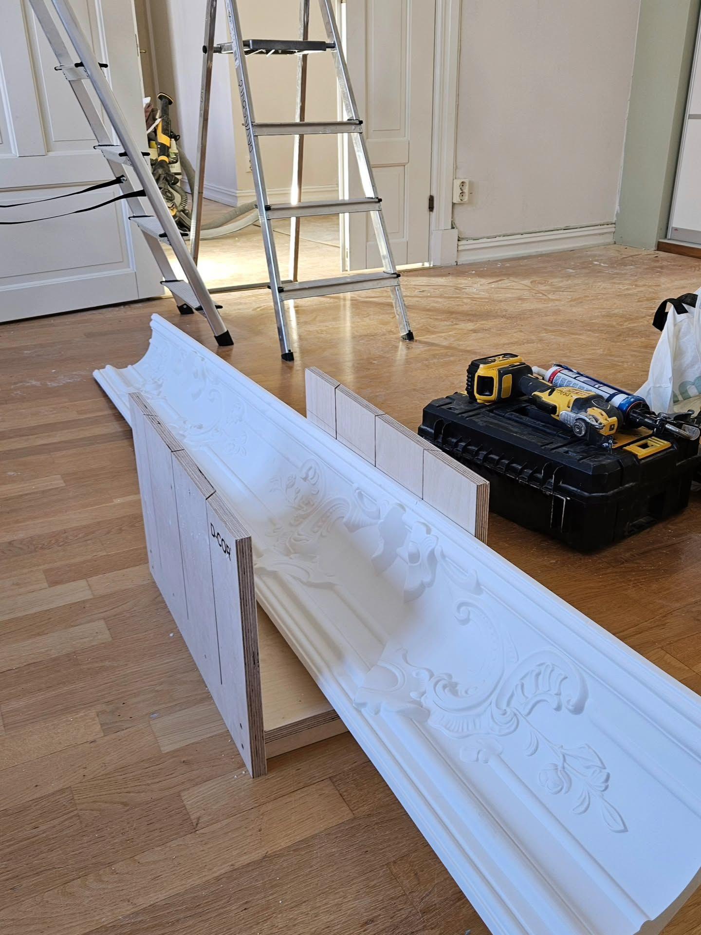 Ornamenterad taklist av gips liggande på golvet vid verktygslåda