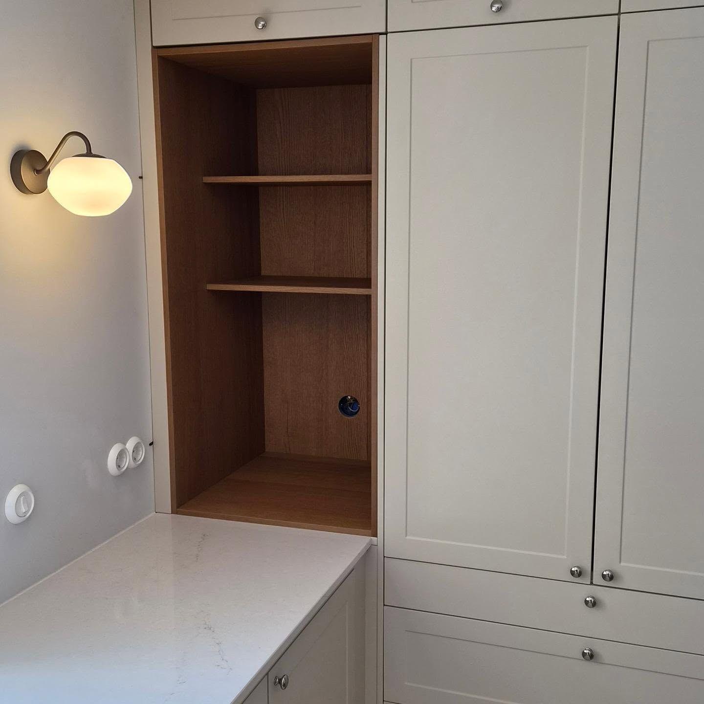 Närbild på den ekklädda nischen med hyllor och vägglampa intill
