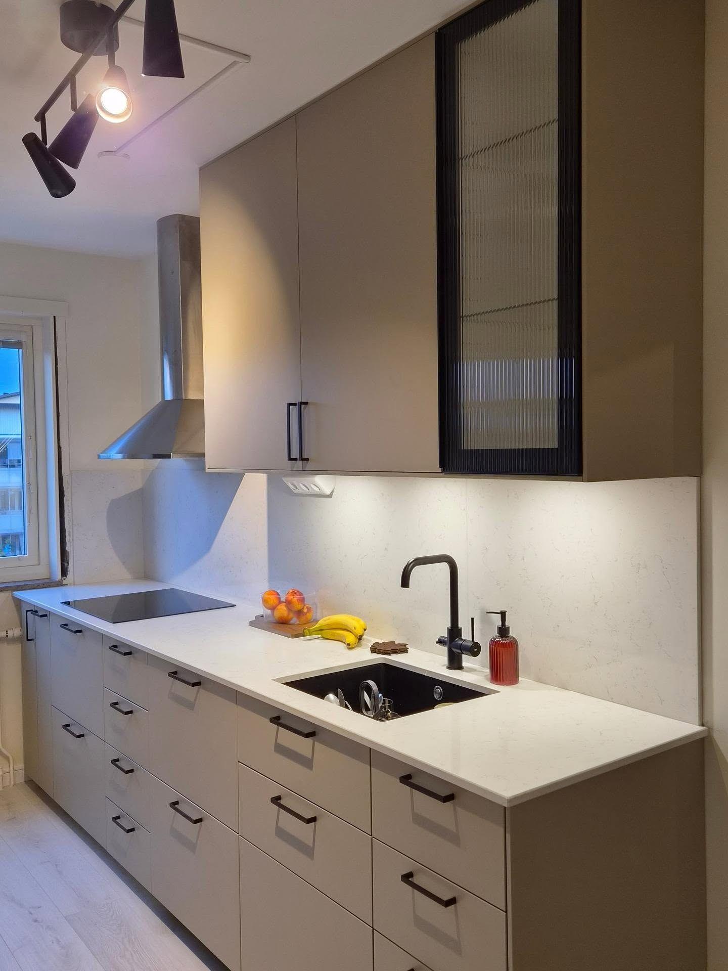 Kök med beige luckor, ljus bänkskiva och svart blandare monterat av Pavas Bygg i Göteborg